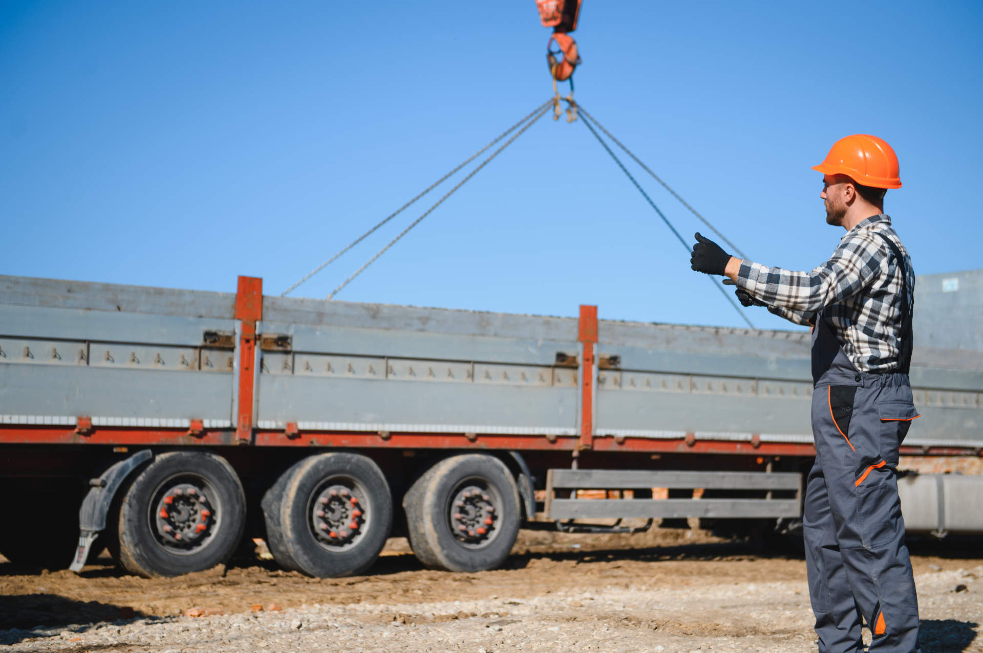 A builder controls a crane while unloading panels to cover a house